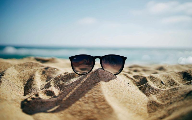 black Ray-Ban Wayfarer sunglasses on beach sand